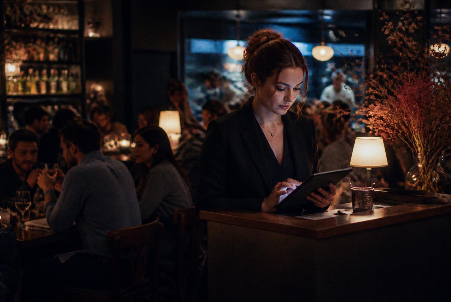 A restaurant manager checking reservations on a tablet